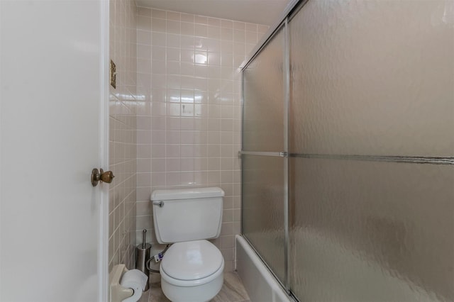 bathroom featuring toilet, enclosed tub / shower combo, and tile walls