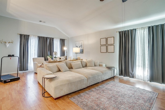 living room with lofted ceiling, light wood-type flooring, and plenty of natural light