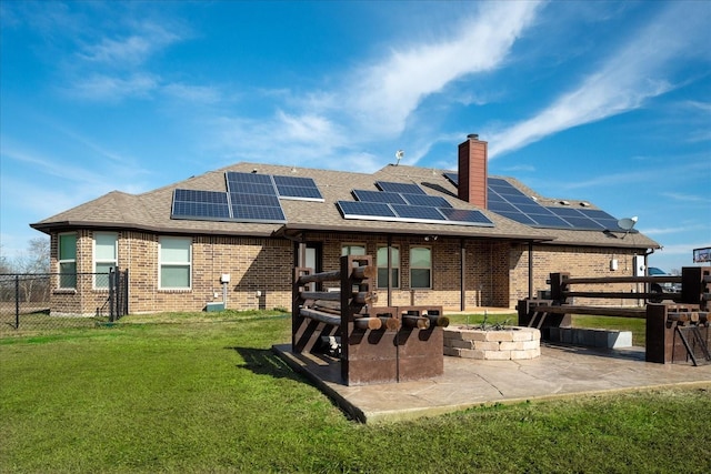 back of house with a patio area, a lawn, and solar panels