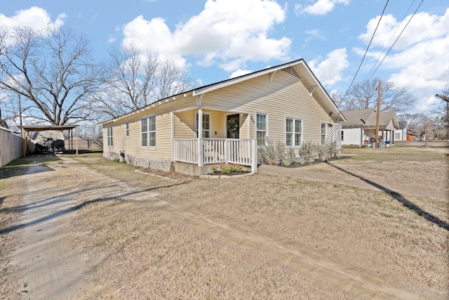 view of front of house with a front lawn, a carport, and covered porch