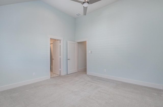 carpeted empty room with ceiling fan and high vaulted ceiling