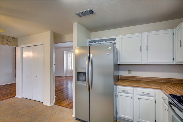 kitchen with light tile patterned floors, appliances with stainless steel finishes, and white cabinetry