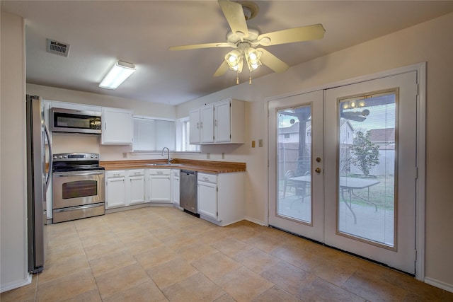 kitchen featuring wooden counters, white cabinetry, stainless steel appliances, french doors, and sink