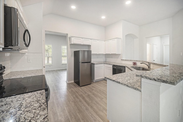 kitchen featuring white cabinets, a sink, appliances with stainless steel finishes, backsplash, and light stone counters