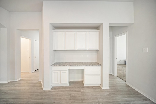unfurnished office featuring light wood finished floors, built in study area, and baseboards