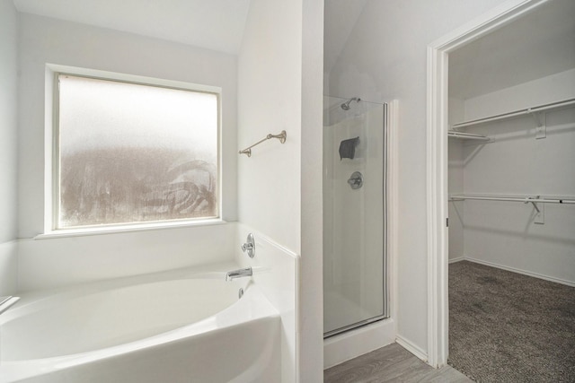 full bath with a spacious closet, a bath, and a stall shower