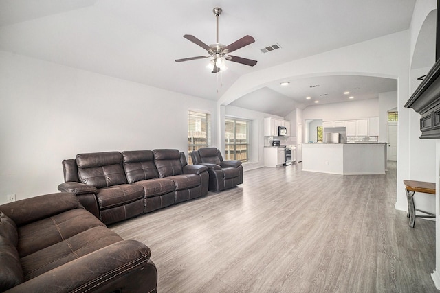living room with arched walkways, a ceiling fan, visible vents, lofted ceiling, and light wood finished floors