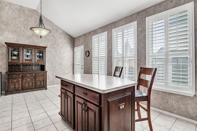 kitchen featuring hanging light fixtures, a kitchen island, light tile patterned floors, and dark brown cabinetry