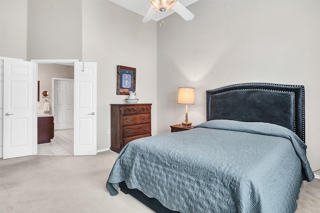 bedroom featuring a high ceiling, light colored carpet, and ceiling fan