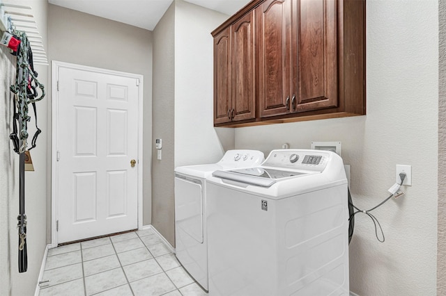 laundry room featuring cabinets, light tile patterned flooring, and washer and dryer