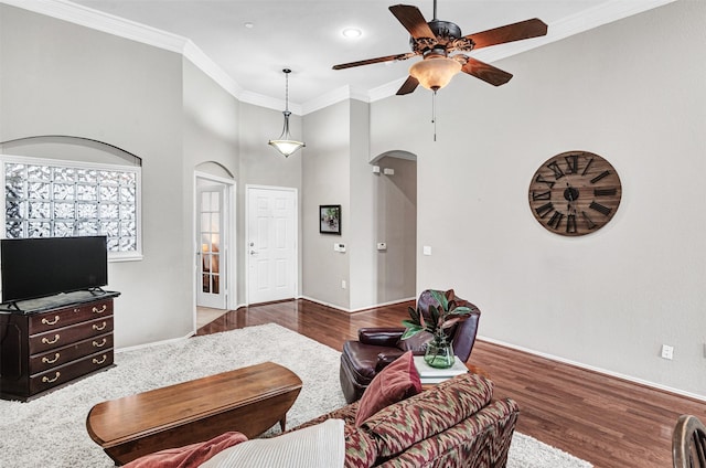 living room with a high ceiling, crown molding, wood-type flooring, and ceiling fan