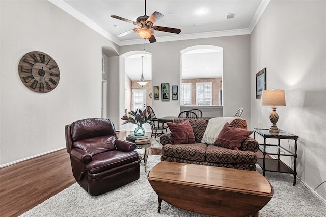 living room with hardwood / wood-style floors, crown molding, and ceiling fan