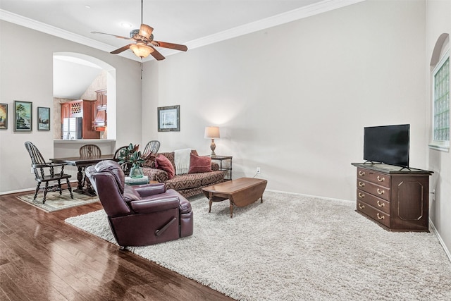 living room with wood-type flooring, ornamental molding, and ceiling fan