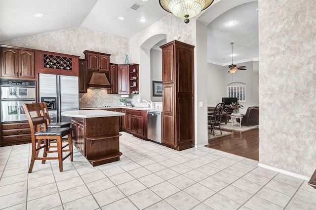 kitchen with light tile patterned floors, stainless steel appliances, a kitchen breakfast bar, ornamental molding, and a kitchen island