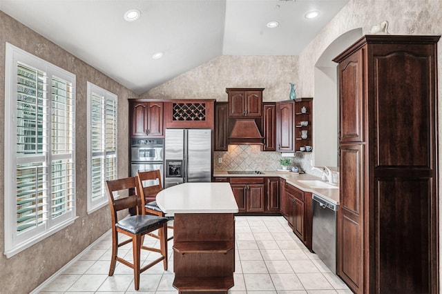 kitchen with lofted ceiling, sink, a center island, appliances with stainless steel finishes, and a wealth of natural light