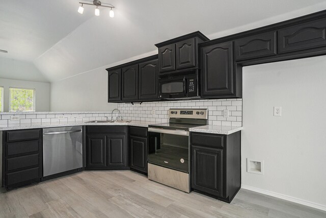 kitchen with a sink, light countertops, vaulted ceiling, stainless steel appliances, and light wood-style flooring