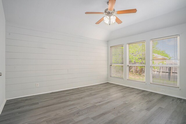unfurnished room with baseboards, a ceiling fan, vaulted ceiling, and wood finished floors