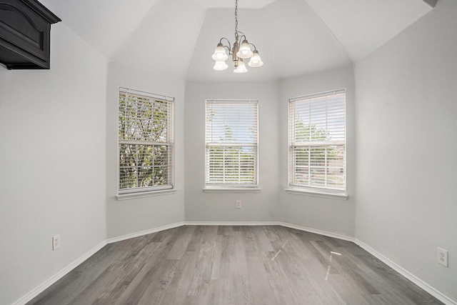 unfurnished dining area with baseboards, vaulted ceiling, an inviting chandelier, and wood finished floors