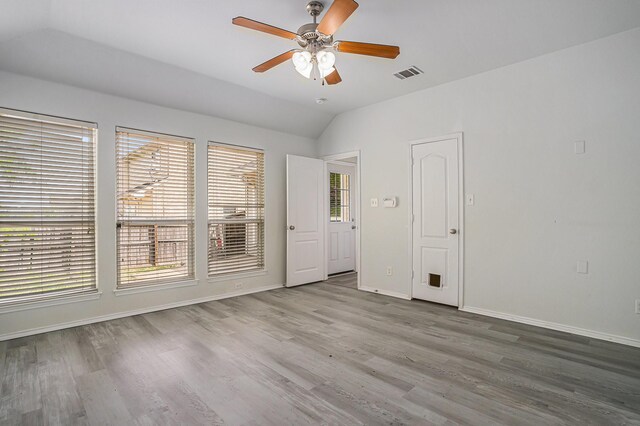 spare room with visible vents, wood finished floors, vaulted ceiling, and a ceiling fan
