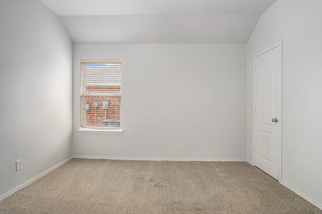 unfurnished room featuring light colored carpet, baseboards, and lofted ceiling