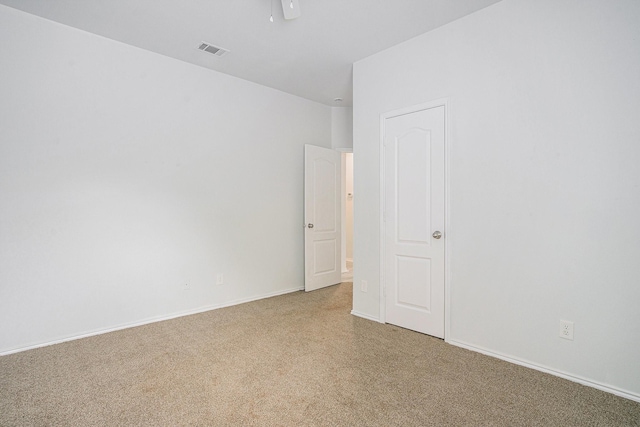 spare room featuring light carpet, visible vents, and baseboards