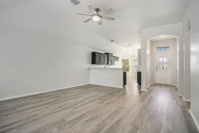 unfurnished living room featuring visible vents, baseboards, wood finished floors, ceiling fan with notable chandelier, and lofted ceiling