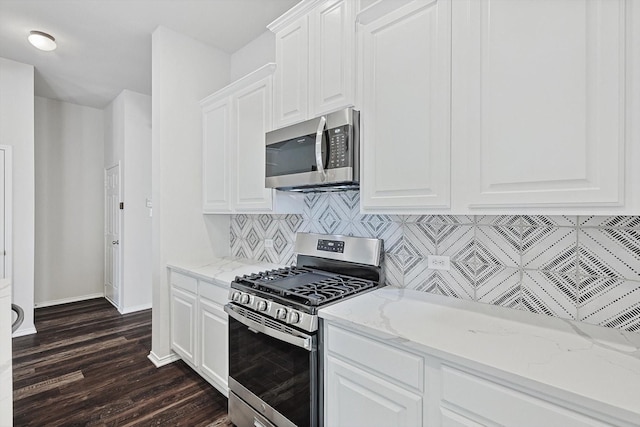 kitchen featuring white cabinetry, tasteful backsplash, light stone counters, dark hardwood / wood-style flooring, and stainless steel appliances