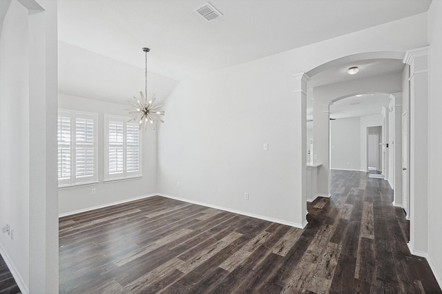 empty room featuring dark wood-type flooring, vaulted ceiling, and an inviting chandelier