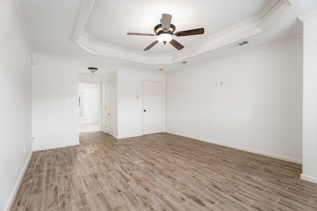 spare room featuring light hardwood / wood-style floors, a tray ceiling, ornamental molding, and ceiling fan