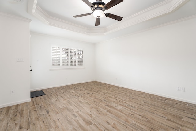 unfurnished room featuring light wood-type flooring, ornamental molding, and a tray ceiling