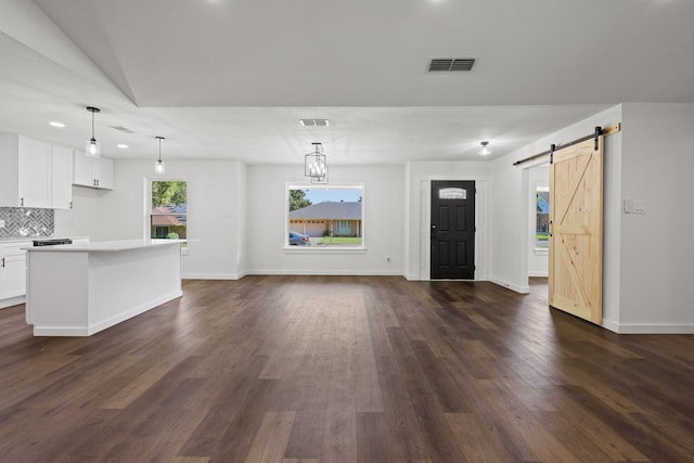 unfurnished living room with a barn door and dark wood-type flooring