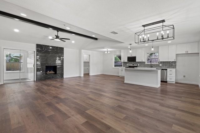 kitchen with a kitchen island, beam ceiling, a premium fireplace, white cabinetry, and hanging light fixtures