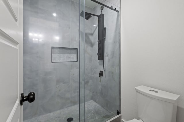 bathroom featuring toilet and a shower with shower door