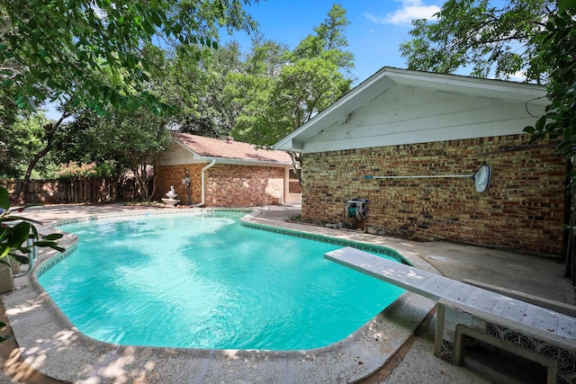 view of swimming pool featuring a patio area and a diving board