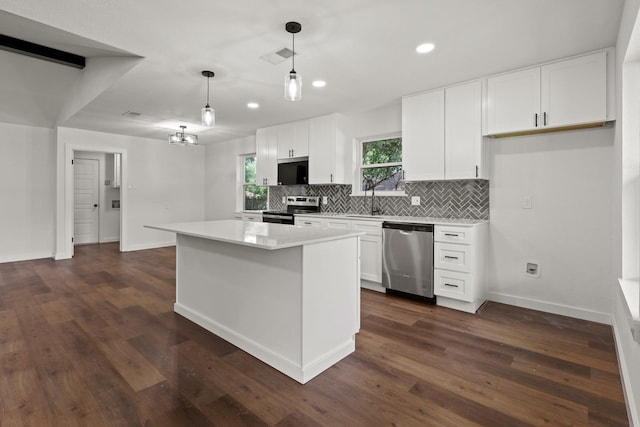 kitchen featuring decorative light fixtures, white cabinetry, appliances with stainless steel finishes, and a center island