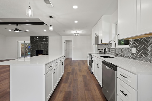 kitchen with appliances with stainless steel finishes, white cabinets, dark hardwood / wood-style flooring, sink, and hanging light fixtures