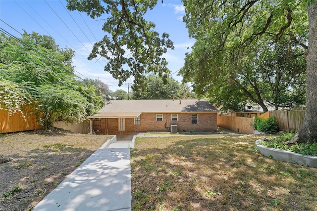 rear view of house with central AC unit and a lawn