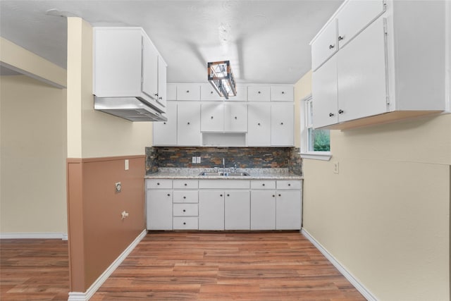 kitchen featuring sink, backsplash, white cabinets, and light hardwood / wood-style flooring