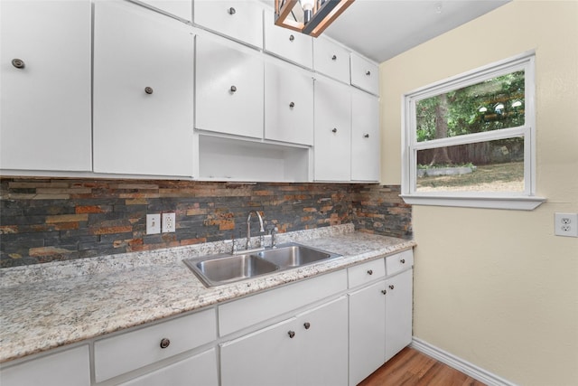 kitchen featuring tasteful backsplash, sink, white cabinetry, and light hardwood / wood-style floors