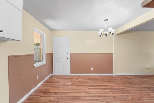 unfurnished dining area with light hardwood / wood-style flooring and an inviting chandelier