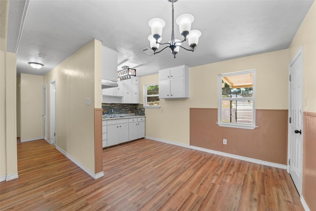 kitchen with tasteful backsplash, decorative light fixtures, light hardwood / wood-style floors, sink, and white cabinets