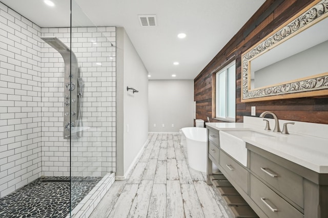 bathroom featuring independent shower and bath, wood walls, and vanity