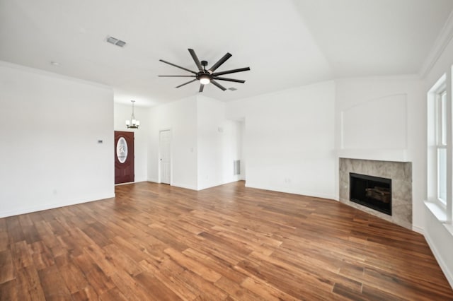 unfurnished living room with hardwood / wood-style flooring, ceiling fan with notable chandelier, a tile fireplace, and crown molding