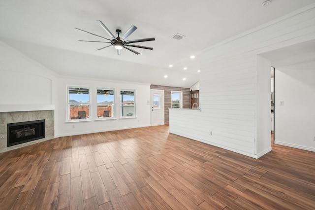 unfurnished living room with ceiling fan, wood-type flooring, a tile fireplace, and vaulted ceiling