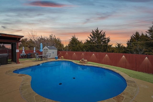 pool at dusk with a patio area and a storage shed