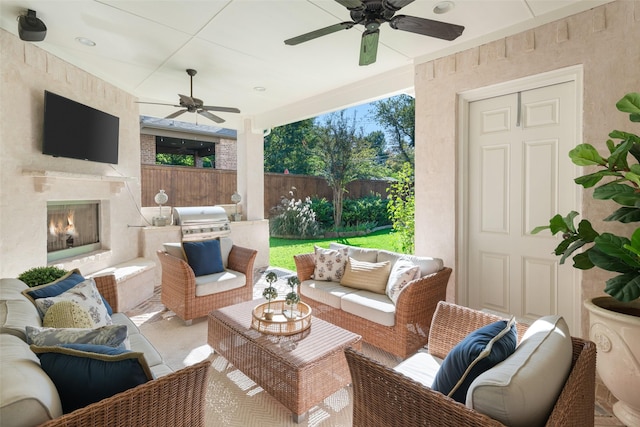 view of patio with an outdoor living space with a fireplace, fence, an outdoor kitchen, and a ceiling fan