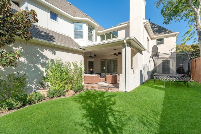 rear view of house featuring a ceiling fan, fence, a trampoline, a patio area, and an outdoor hangout area