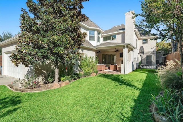 exterior space featuring fence, a lawn, outdoor lounge area, a garage, and a ceiling fan