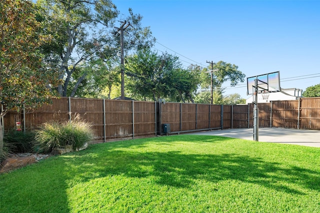 view of yard with basketball court and fence