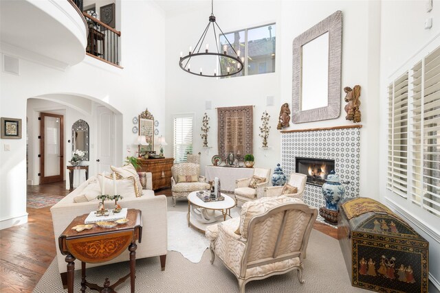 living room featuring hardwood / wood-style flooring, a towering ceiling, a fireplace, and a chandelier